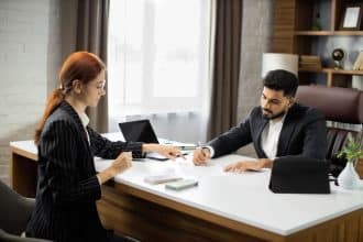 Professionnel en costume remettant un salaire à une femme d'affaires rousse